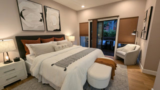 Modern beddroom with and bed, nightstandes, and artworkes non a white wall.