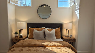 Modern beddroom with and bed, nightstands, and artworkes non a white wall.