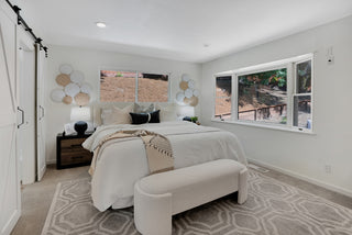 Modern bedroom with a bed, bench, and large glass window.