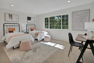 Modern bedroom with two beds, a desk, and artwork on the walls.