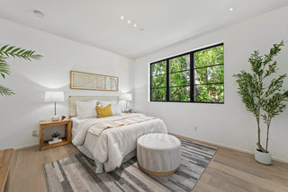 Modern bedroom with a bed, nightstands, and a large window with a view of trees and nature 