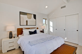 Modern bedroom with a bed, nightstands, and abstract art on the wall.