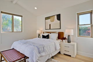 Modern bedroom with a bed, nightstands, and artwork on the wall.