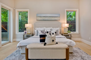 Modern bedroom with a bed, ottoman, and decorative pillows.
