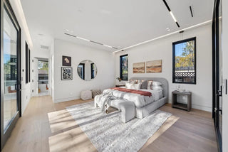 Modern bedroom with a bed, rug, and large windows glass window and wall