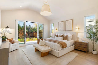 Modern bedroom with a large bed, seating area, and large windows.