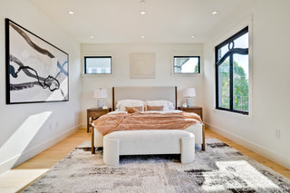 Modern bedroom with a bed, nightstands, and artwork on a white wall.