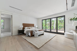 Modern bedroom with large Glass windows,  big room with AC neutral decor, and a rug.