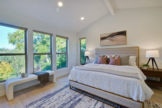 Modern bedroom with large windows, bed, and decorative elements.