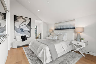 Modern bedroom with a bed, side tables, and abstract art on the walls.