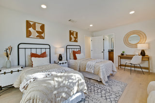 Modern bedroom with two beds, decorative pillows, and a side table.