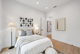 Modern bedroom with white walls, a bed with and decorative art pieces  ,gray bedding, 