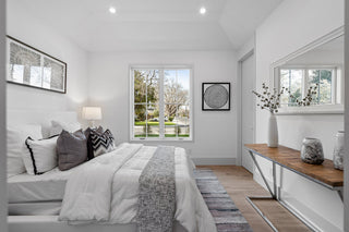 Modern bedroom with white walls, a bed with gray and white bedding, and a wooden console table.