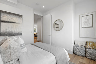 Modern bedroom with white walls, a bed with gray bedding, and decorative pillows.