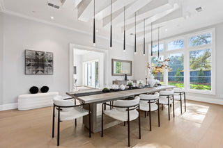Modern dining room with a long table and chairs, large windows, and decorative elements.
