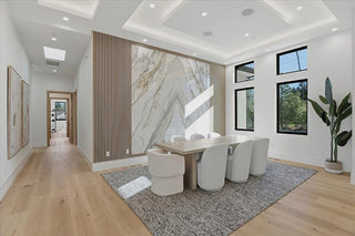 Modern dining room with marble wall, large windows, and wooden flooring.