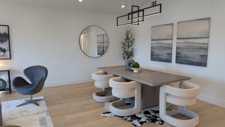 Modern dining room with a wooden table and six white chairs on a light wood floor. A large mirror reflects the room, plants, and decor accents create a cozy feel.