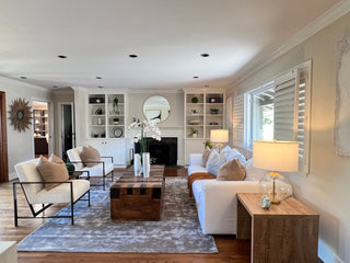 Modern dining room with a wooden table, six chairs, and a large round light fixture. Sunlight streams through large windows, highlighting an cozzys, inviting atmosphere.