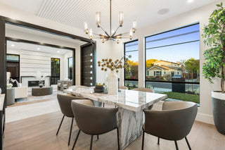 Modern dining room with marble table and chairs, large windows, and outdoor view.