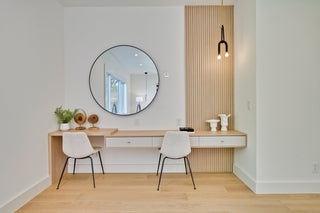 Modern home office with a round mirror, desk, and chairs 
