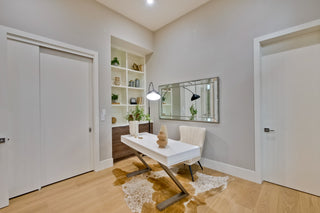Modern home office with desk, shelves, and decorative items.