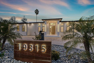Modern house with palm trees and a decorative house number sign.