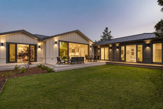 Modern house exterior with open doors, outdoor furniture, and well-maintained lawn evening view