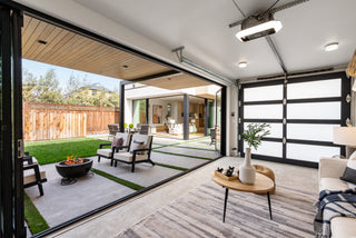 Modern living room with large glass doors leading to a backyard with a fire pit.
