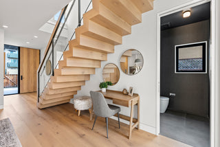 Modern interior with wooden staircase, desk, and round mirrors.