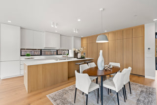 Modern kitchen with wooden cabinets, white countertops, and a dining area.