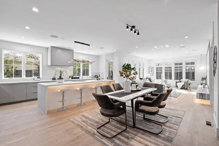 Modern kitchen and dining area with white cabinets, wooden flooring, and decorative elements.