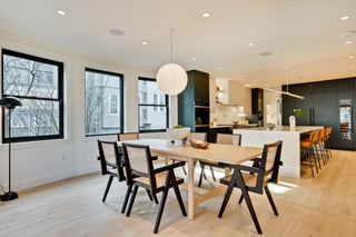 Modern kitchen and dining area with wooden table and chairs, large windows, and a kitchen island.