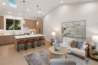 Modern kitchen and living room with a kitchen island, stools, and a sofa with a blanket. with window