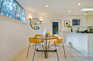Modern kitchen with dining area featuring a round table and yellow chairs.