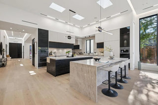 Modern kitchen with marble island and black appliances with small glass wall 