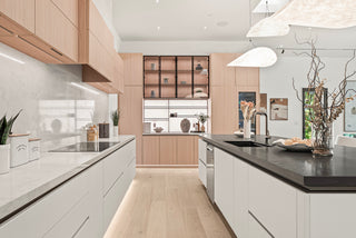 Modern kitchen with sleek wood and white cabinetry, black countertops, and elegant decor. Natural light highlights clean lines and a spacious layout.