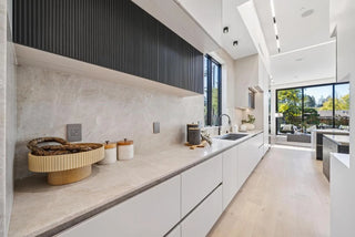Modern kitchen with white cabinetry and gray backsplash far glass doors