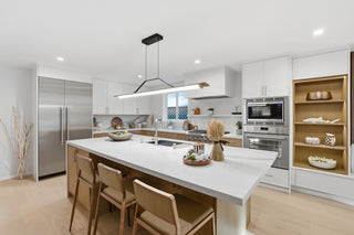 Modern kitchen with white island, stainless steel appliances, and wooden chairs.