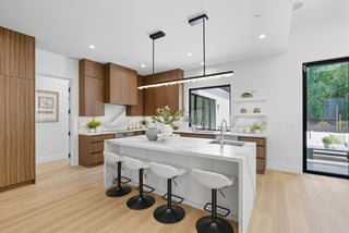 Modern kitchen with wooden cabinets, white island, and black bar stools.