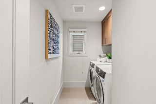 Laundry room with washing machines, dryer, and a piece of abstract art on the wall.