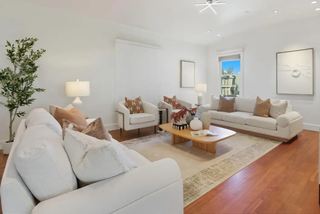 Modern living room with white sofas, coffee table, and decorative items.
