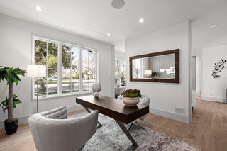 Modern living room with a large window, wooden table, and gray armchair.