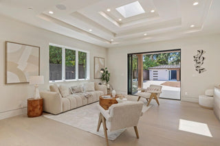 Modern living room with beige sofa, armchair, and coffee table. and outdoor view with glass door and window
