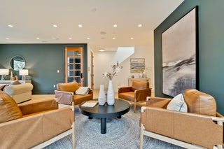 Modern living room with brown leather furniture and abstract art on the wall.