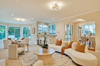Modern living room with white furniture, large windows, and decorative elements.
