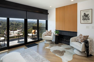 Modern living room with a fireplace, armchairs, and a view of a cityscape.