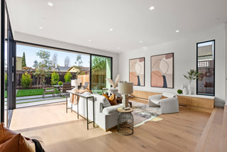 Modern living room with large windows, white furniture, and decorative elements.