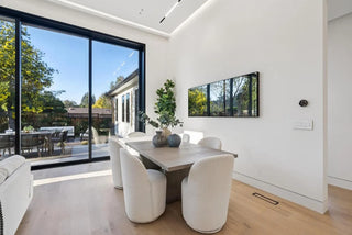 Modern living room with large windows, beige sofa, and wooden coffee table glass wall side view nature through glass