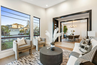 Modern living room with large windows, furniture, and decor.