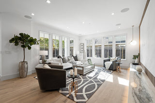 Modern living room with large windows, neutral decor, and a rug.